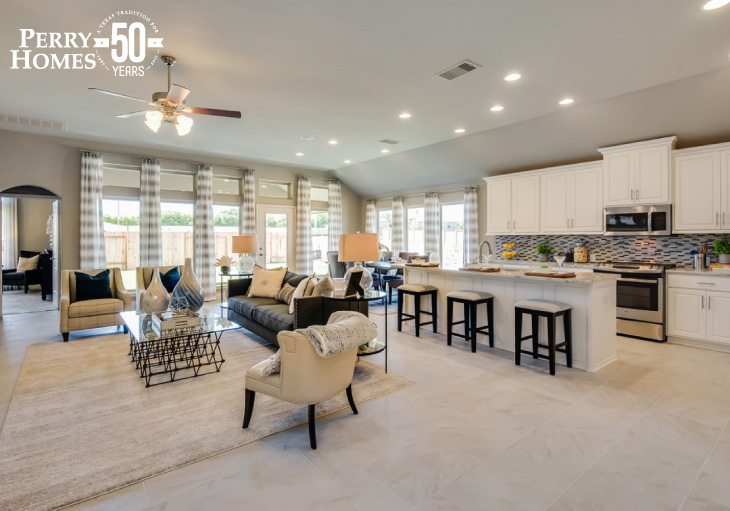 open concept interior with family room, dining area and kitchen with white cabinets, island with seating and large windows