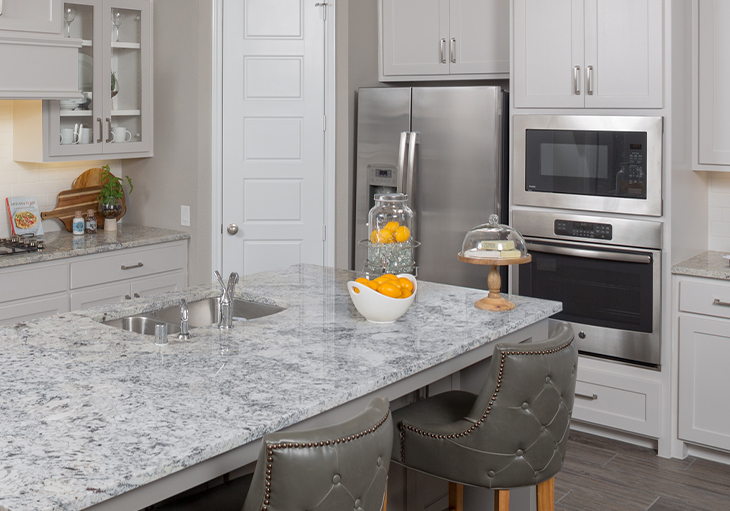 A modern kitchen in a Perry home features a grey and white countertop and off-white shaker cabinets.