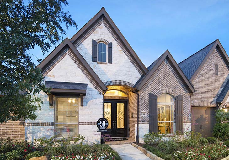 one story home exterior with double front doors, beige stone, brown brick herringbone pattern, arched windows with shutters