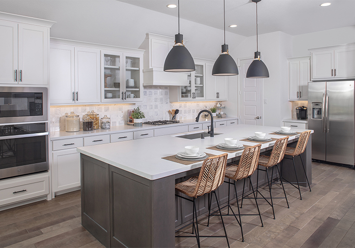 Modern, neutral kitchen in a naturally lit Texas home with large island, white cabinets, stainless steel appliances