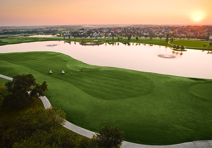 An aerial view of a golf course with a sunset in the 
background.
