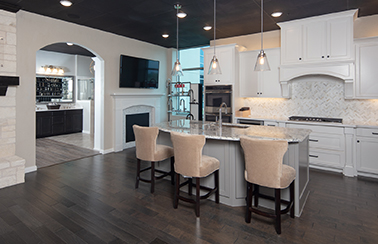 display area of Perry Homes dallas design center with white kitchen cabinets, grey center island and pendant lights