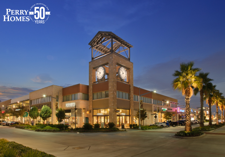 pearland town center clock tower at night time with store lights shining and palm trees with landscaping lighting