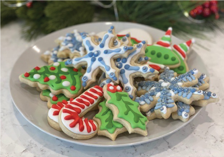 Plate of sugar cookies in various holiday shapes decorated with colorful frosting.