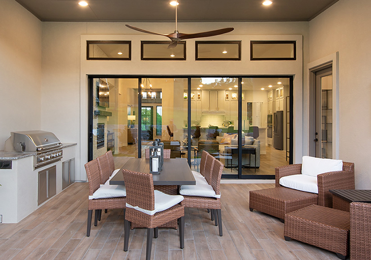 An outdoor living area with brown wicker furniture and a built-in grill.
